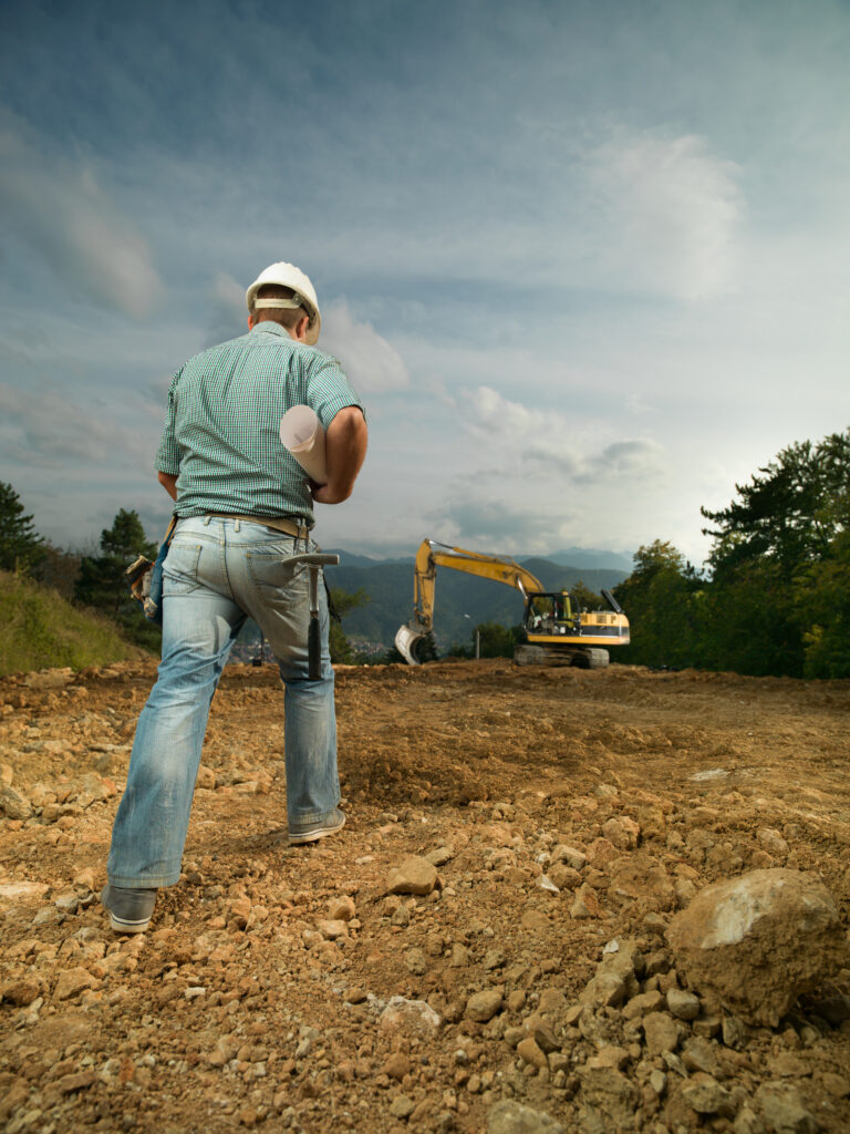 Expert en terrassement à Sérézin-du-Rhône supervisant un chantier avec une pelleteuse en arrière-plan.